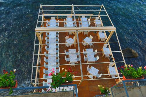 a balcony with white chairs and flowers on the water at Il Casato Deluxe Rooms in Scilla