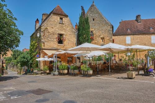a street with tables and umbrellas in front of a building at Village de Montmarsis in Gourdon-en-quercy