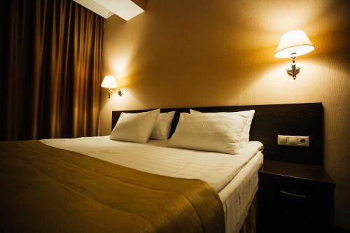 a bedroom with a bed with two lamps on the wall at Hotel Aner in Astana