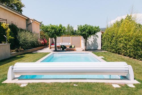 a swimming pool with a bench in the grass at L'ancien poulailler- The Old Hen House in Saint-Saturnin-dʼApt