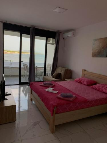 Schlafzimmer mit einem Bett mit roter Bettwäsche und Meerblick in der Unterkunft Sea Star Apartments in Ulcinj