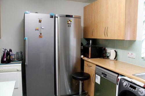 a stainless steel refrigerator in a kitchen with wooden cabinets at Central London rooms in London