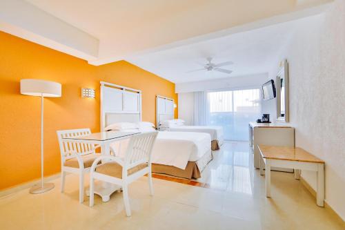 1 dormitorio con 1 cama, mesa y sillas en Occidental Costa Cancún - All Inclusive, en Cancún