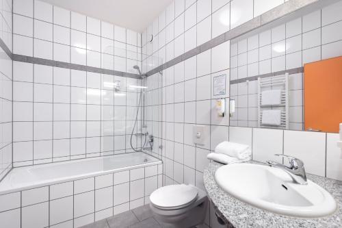 a bathroom with a sink and a toilet and a tub at smartMotel in Kempten