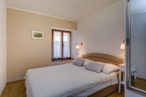 a bedroom with a large white bed and a mirror at Beautiful Apartment Jelena 1 in Veli Lošinj