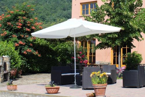 a white umbrella and chairs and flowers in pots at Casa Re - B&B e Vino a Montabone in Montabone