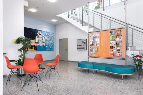 a waiting room with orange chairs and a table at smartMotel in Kempten