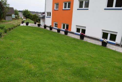 a green yard next to a building with flowers in pots at hunsruecker-fewo - Die Erlebnishütte - 2 Ferienwohnungen im Hunsrück in Unzenberg in Unzenberg