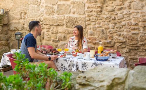 Un hombre y una mujer sentados en una mesa comiendo comida en Hotel La Freixera, en Solsona