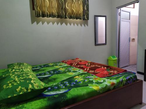 a bedroom with a bed with a colorful comforter at Ijen Bondowoso Home Stay in Bondowoso