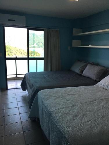 a hotel room with two beds and a large window at Porto Real The View in Mangaratiba