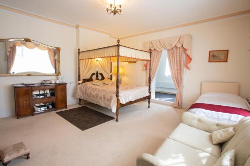 a bedroom with a four poster bed and a couch at Fines Bayliwick Hotel in Bracknell