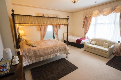 a bedroom with a canopy bed and a couch and a chair at Fines Bayliwick Hotel in Bracknell