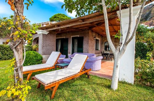 a backyard with two lounge chairs and a house at Tenuta Del Poggio Antico in Ischia