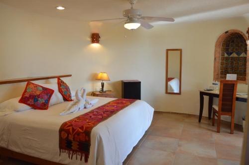a bedroom with a bed and a desk and a ceiling fan at Hotel La Joya Isla Mujeres in Isla Mujeres