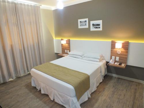 a hotel room with a bed and two lamps at JB Palace Hotel in Divinópolis