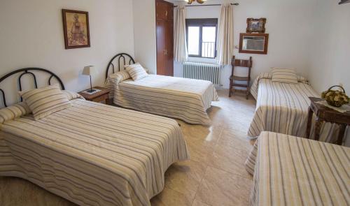 a hotel room with three beds with striped sheets at Hostal Alba Taruta in Guadalupe