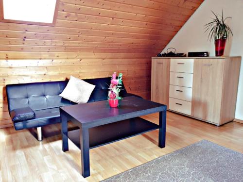 a living room with a black leather couch and a table at VOLL ausgestattete DG- Wohnung in HDH ruhige zentrale Lage in Heidenheim an der Brenz