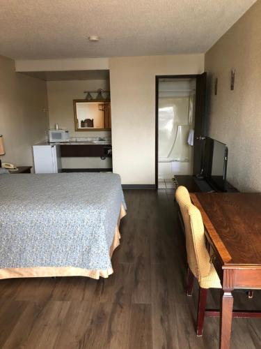 a bedroom with a bed and a table and a kitchen at Red Deer Inn & Suites in Red Deer