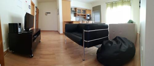 a living room with black chairs and a television at Flat Sines in Sines