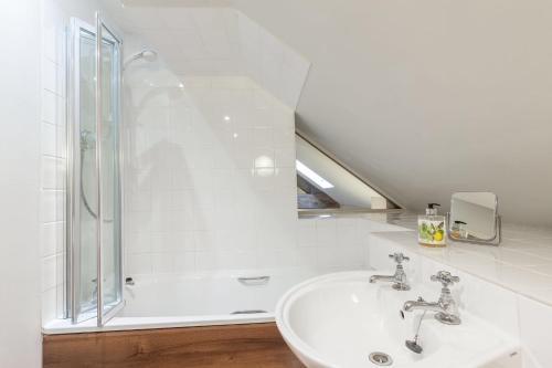 a white bathroom with a shower and a sink at The Coach House Holiday Home in Stony Middleton