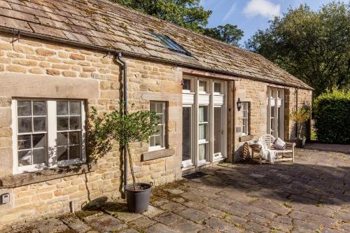 a brick house with a potted tree in front of it at The Coach House Holiday Home in Stoney Middleton
