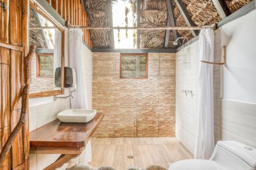 ein Badezimmer mit 2 WCs, einem Waschbecken und einer Dusche in der Unterkunft Selina Amazon Tena in Tena