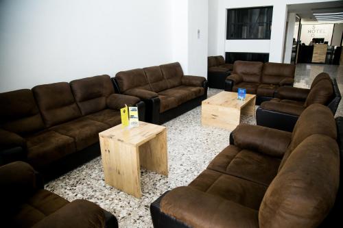 a living room with brown leather couches and tables at Booking 500 in Monterrey