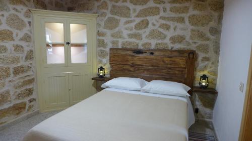 sypialnia z białym łóżkiem i kamienną ścianą w obiekcie Casas da Villa - Monsanto - Oliveira e Videira w mieście Relva