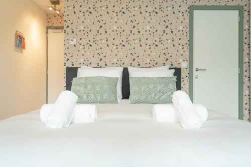 a bedroom with a white bed with green pillows at SHWAY - The Card Room Green Studio in Antwerp