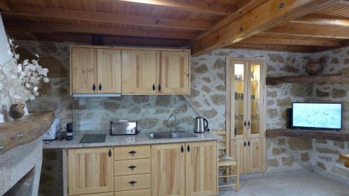 a kitchen with wooden cabinets and a sink at Casas da Villa - Monsanto - Oliveira e Videira in Relva