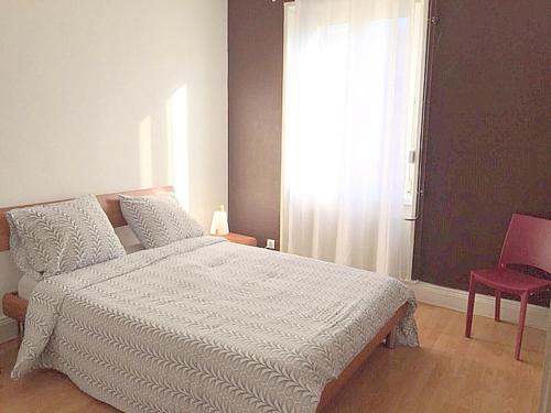 une chambre avec un lit blanc et une chaise rouge dans l'établissement Le MONTREAL F3 (2 chambres) Centre Ville/ GareTGV, à Mulhouse