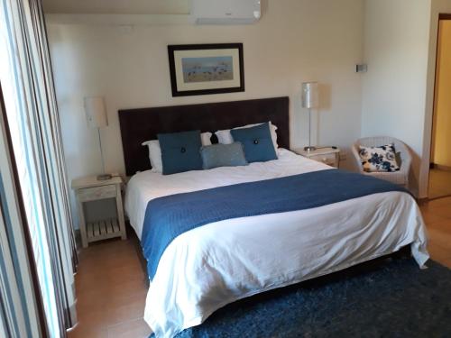 a bedroom with a large bed with blue pillows at The Shore's in Southbroom