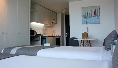 two beds in a small room with a kitchen at EcoApart Antofagasta in Antofagasta