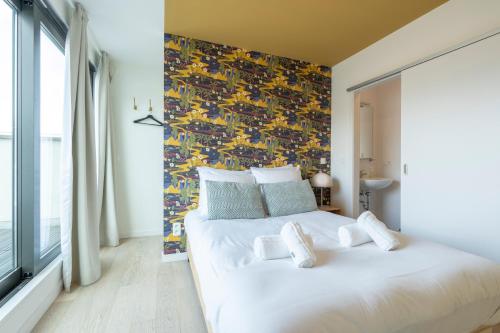 a bedroom with a white bed with a colorful wall at The India Yellow Studio in Antwerp