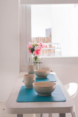 a table with three bowls and a vase with flowers at Soho Point Central in Buenos Aires