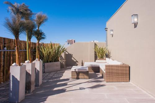 a patio with wicker furniture and palm trees and a building at Soho Point Central in Buenos Aires