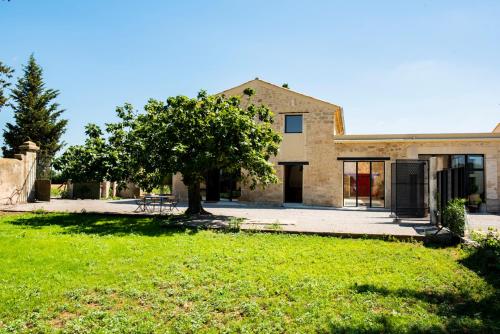 a house with a tree in front of a yard at Domaine la Clausade in Mauguio