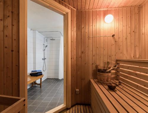 a bathroom with a shower and a wooden wall at Borrgården Hostel in Ljusdal