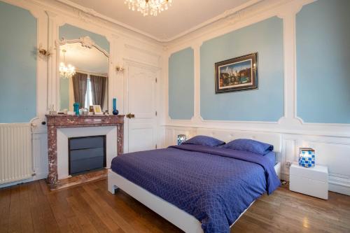 a blue bedroom with a bed and a fireplace at L'Escale de Jules et Lily in Bligny-lès-Beaune