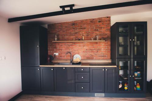 una cocina con armarios negros y una pared de ladrillo en Pasieka Smakulskich, en Pakosław