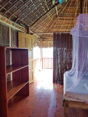 a bedroom with a bed and a room with a wooden floor at San Blas Islands - Private Cabin Over-the-Ocean including Meals in Mandinga
