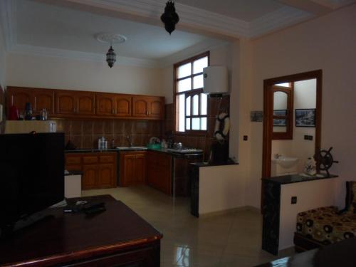 a large kitchen with wooden cabinets and a television at Seaside House in Imsouane