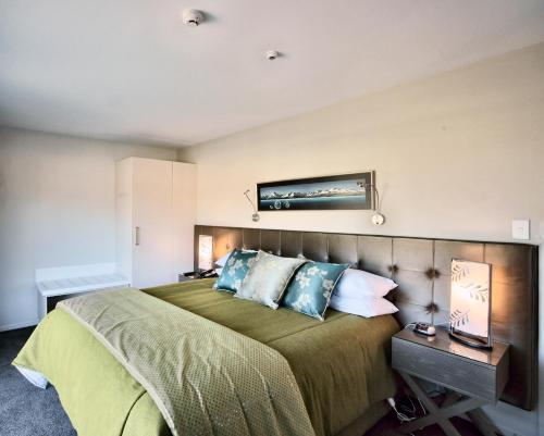 a bedroom with a large bed with blue pillows at The St James Premium Accommodation in Hanmer Springs