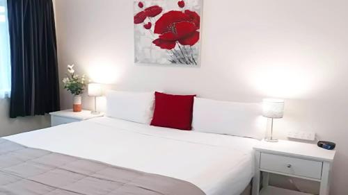 a bedroom with a white bed with red pillows at Almond Court Motel in Alexandra