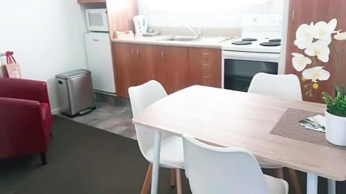 a kitchen with a wooden table and white chairs at Almond Court Motel in Alexandra