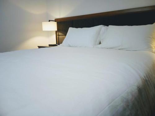 a large bed with white sheets and pillows at Winning Post Motor Inn in Mudgee