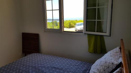 um quarto com uma cama e uma janela em Planète Bleue Habitation mes DESIRS em Beaurenom