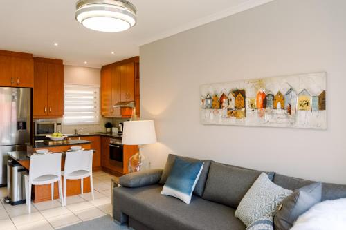 a living room with a couch and a kitchen at Serenity on Oribi in Jeffreys Bay