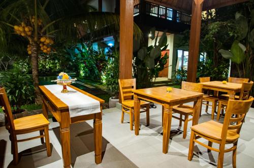 a restaurant with wooden tables and chairs on a patio at Flamboyant Villa Ubud in Ubud
